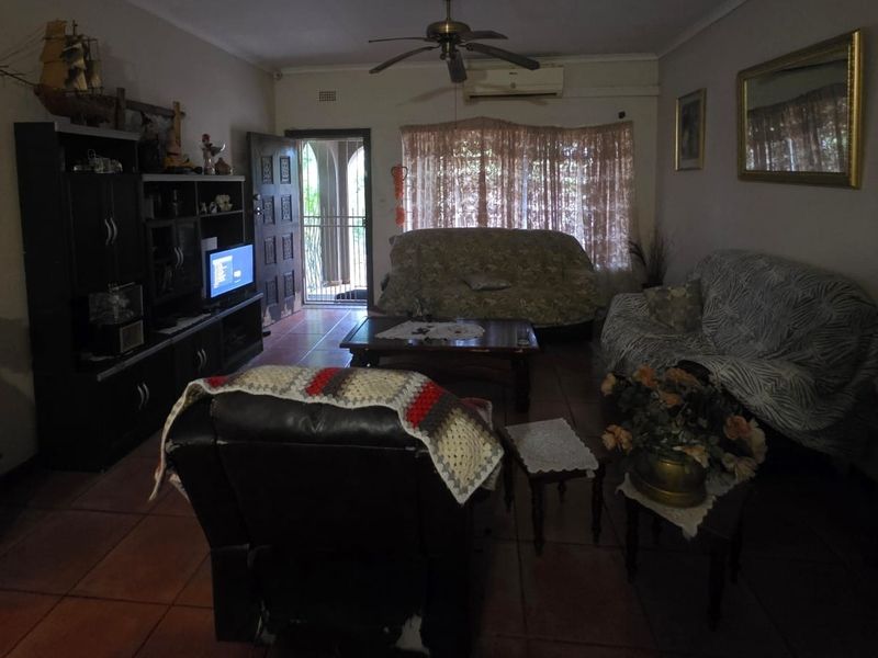 A living room featuring tiled flooring, a ceiling fan, and a wall-mounted air conditioning unit, providing a functional and comfortable living space.