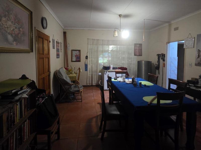 A dining room featuring tiled flooring and a timber door, providing a functional space for family meals.