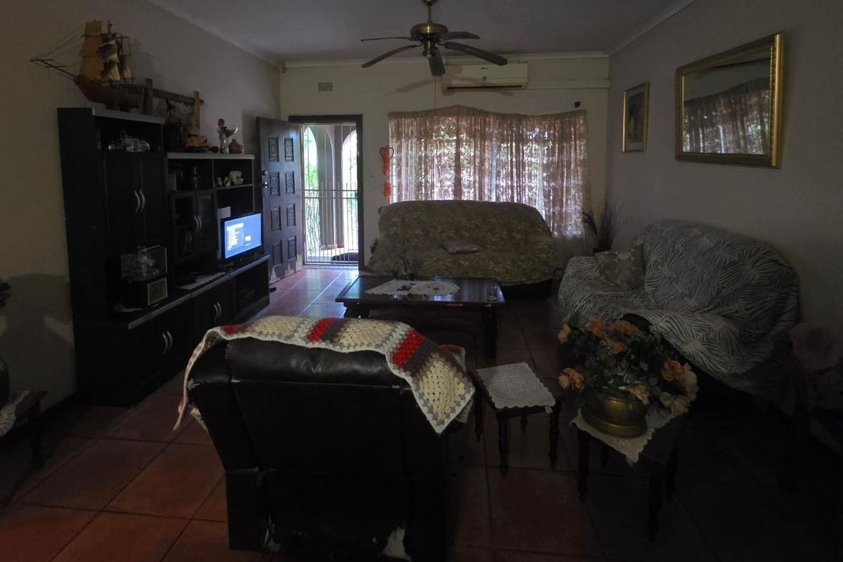 A living room featuring tiled flooring, a ceiling fan, and a wall-mounted air conditioning unit, providing a functional and comfortable living space.