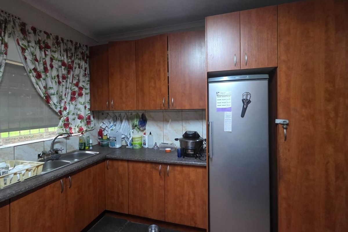 A functional kitchen featuring wood-look laminate cabinetry, durable countertops, and a double bowl stainless steel sink with a tiled backsplash.