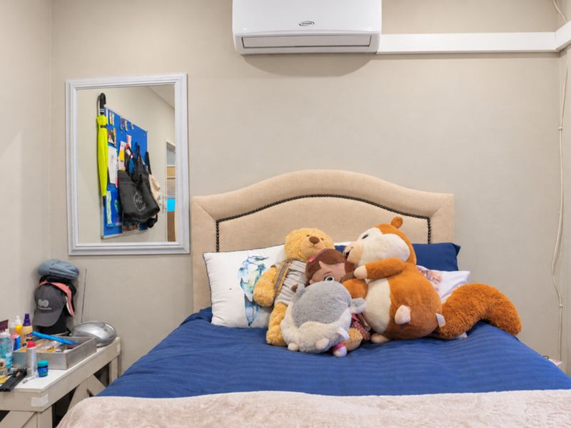 A bedroom featuring a wall-mounted split-system air conditioner and neutral wall finishes.