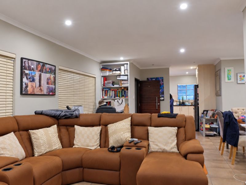 Spacious open-plan living area featuring tiled flooring, recessed downlighting, and neutral wall finishes, seamlessly connecting to the kitchen and dining space.