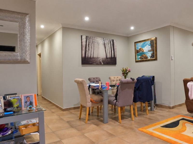 A well-maintained dining area featuring neutral wall tones, tiled flooring, and recessed downlighting, creating a functional and inviting space for meals.