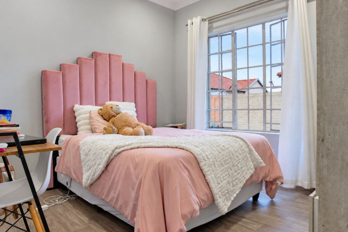 A well-lit bedroom featuring laminate flooring and a large steel-framed window, providing a bright and comfortable living space.