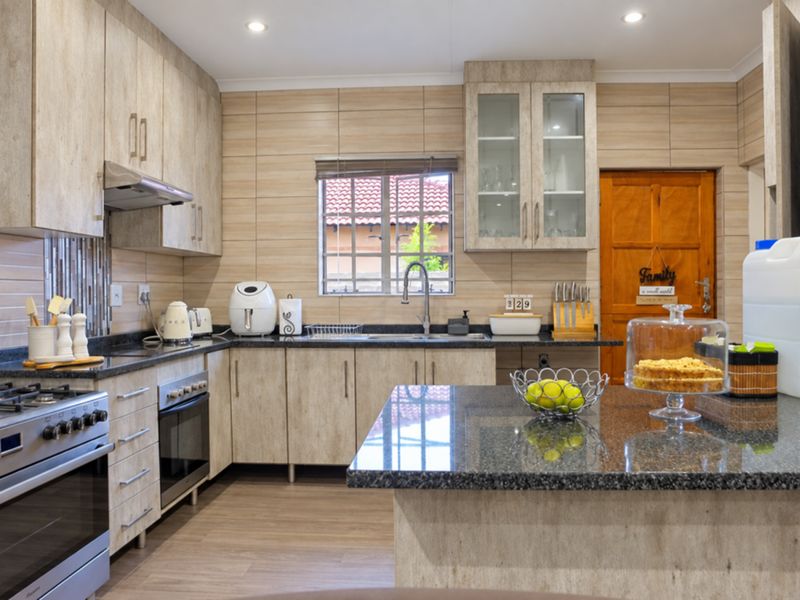 Modern kitchen featuring granite countertops, ample built-in cabinetry, stainless steel gas stove with extractor, and a functional layout with a central island.