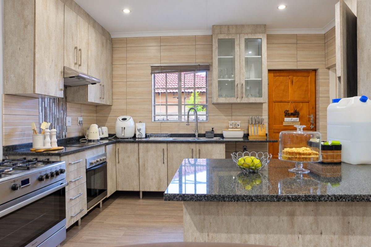 Modern kitchen featuring granite countertops, ample built-in cabinetry, stainless steel gas stove with extractor, and a functional layout with a central island.