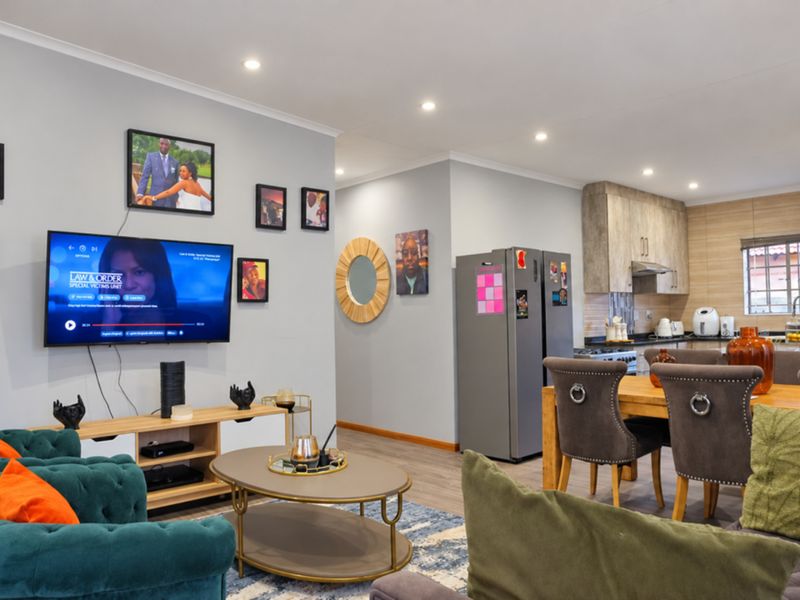 An open-plan living and dining area featuring recessed lighting, laminate flooring, and a modern kitchen with built-in cabinetry and a tiled backsplash.