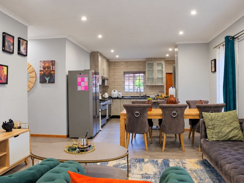 An open-plan living, dining, and kitchen area featuring modern cabinetry, recessed lighting, and laminate flooring, creating a cohesive and functional living space.