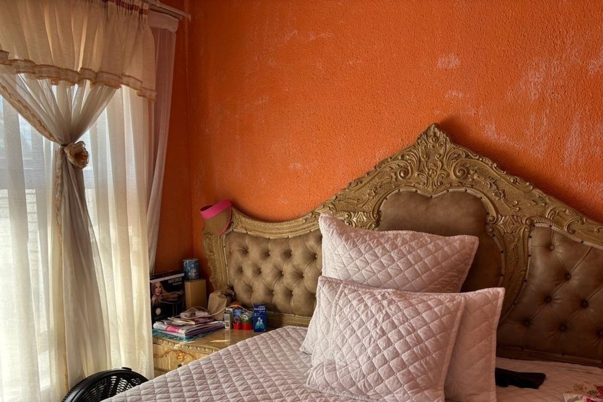 A bedroom featuring a textured orange wall finish and a large ornate headboard.