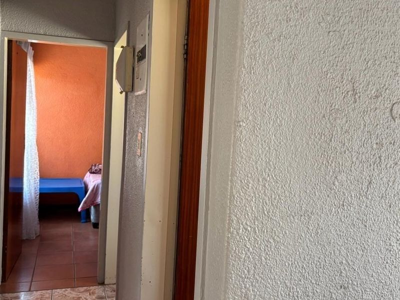 A narrow interior hallway featuring textured walls and access to adjacent rooms, showing signs of wear and dated finishes.