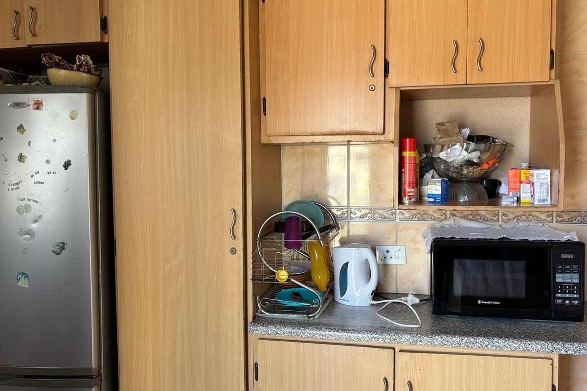 A dated kitchen featuring laminate cabinetry, tiled backsplash, and a built-in microwave area, offering potential for a modern renovation.