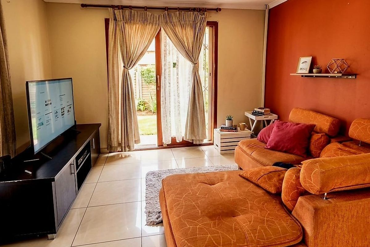A comfortable living room featuring tiled flooring and a sliding glass door providing direct access to the outdoor area.