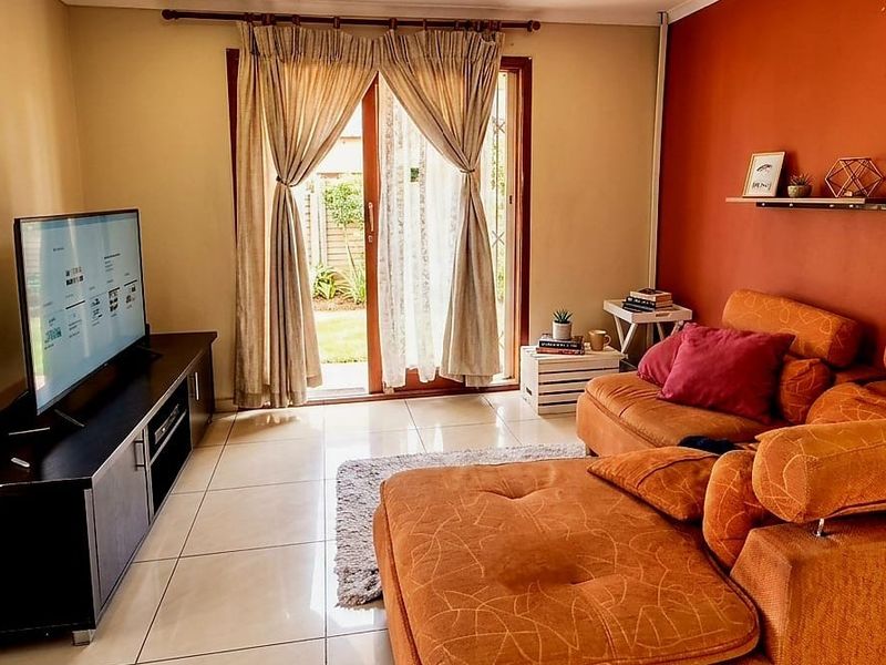 A comfortable living room featuring tiled flooring and a sliding glass door providing direct access to the outdoor area.