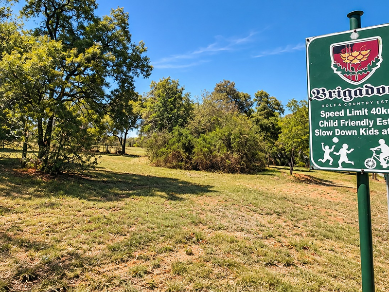A view of the entrance area to the Brigadoon Golf and Country Estate, featuring established trees and open green space.