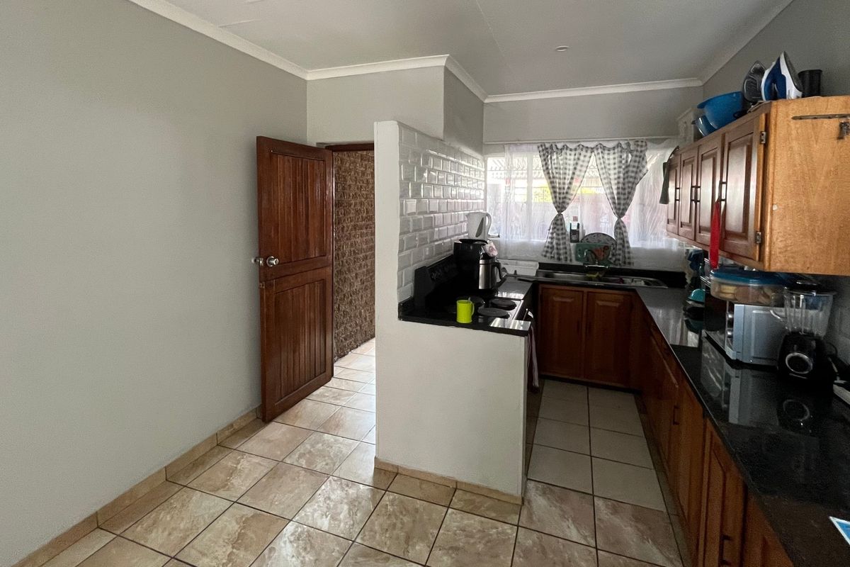 Functional kitchen featuring wooden cabinetry, granite countertops, subway tile backsplash, and ceramic floor tiles with a convenient layout.