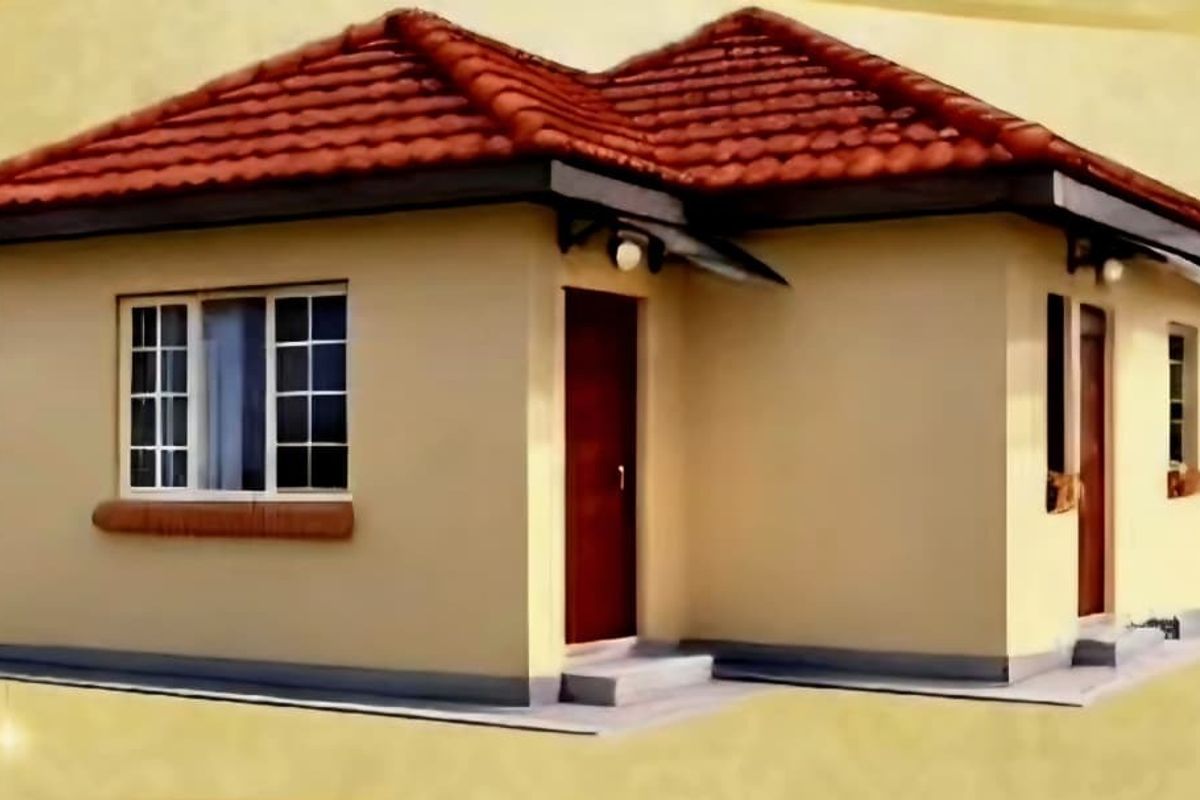A compact, well-maintained single-story house featuring a tiled roof, plastered exterior walls, and aluminium window frames.