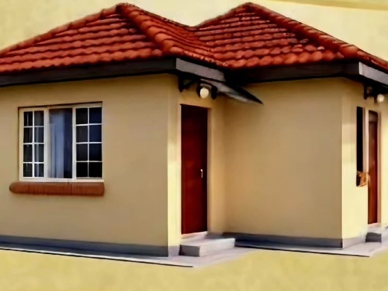 A compact, well-maintained single-story house featuring a tiled roof, plastered exterior walls, and aluminium window frames.