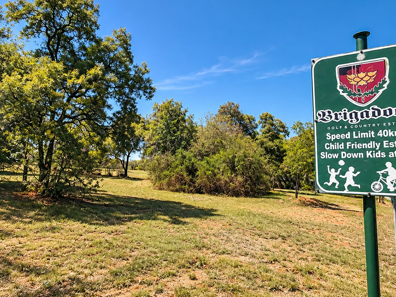 Entrance view of the Brigadoon Golf & Country Estate featuring established trees and estate signage.