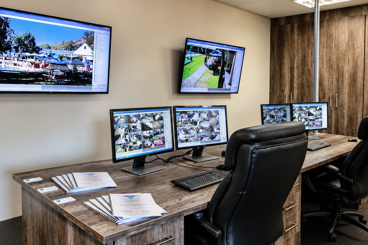 A professional office or security monitoring room featuring built-in wood-finish cabinetry and a clean, functional workspace layout.