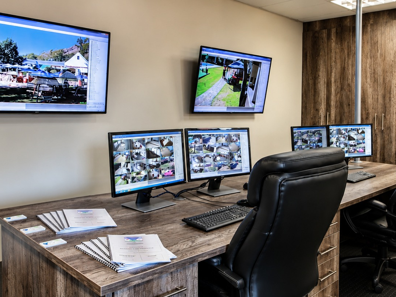 A professional office or security monitoring room featuring built-in wood-finish cabinetry and a clean, functional workspace layout.