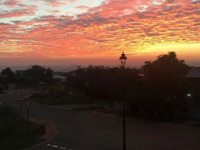 A scenic view of the neighbourhood at sunset, featuring a clear sky and local street infrastructure.