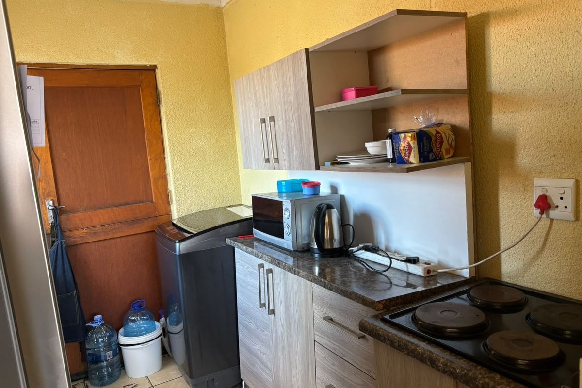 A compact kitchen area featuring built-in cabinetry, laminate countertops, and an electric hob, requiring cosmetic updates to improve the overall finish.