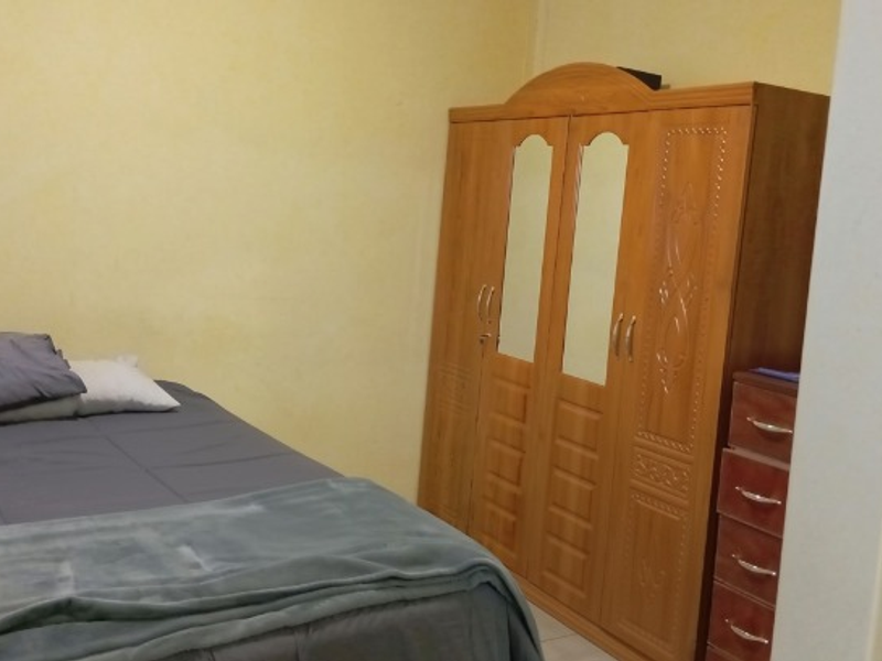 A standard bedroom featuring plain walls and neutral flooring, providing a functional space for rest.
