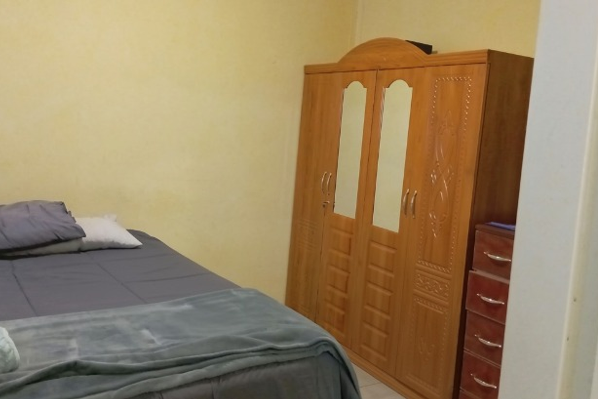 A standard bedroom featuring plain walls and neutral flooring, providing a functional space for rest.