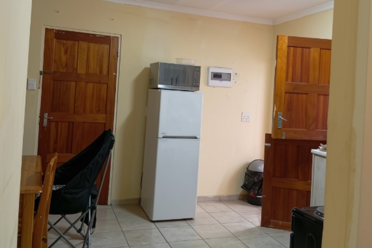 A functional kitchen area featuring tiled flooring and wooden doors, requiring cosmetic updates to improve the overall aesthetic and finish.