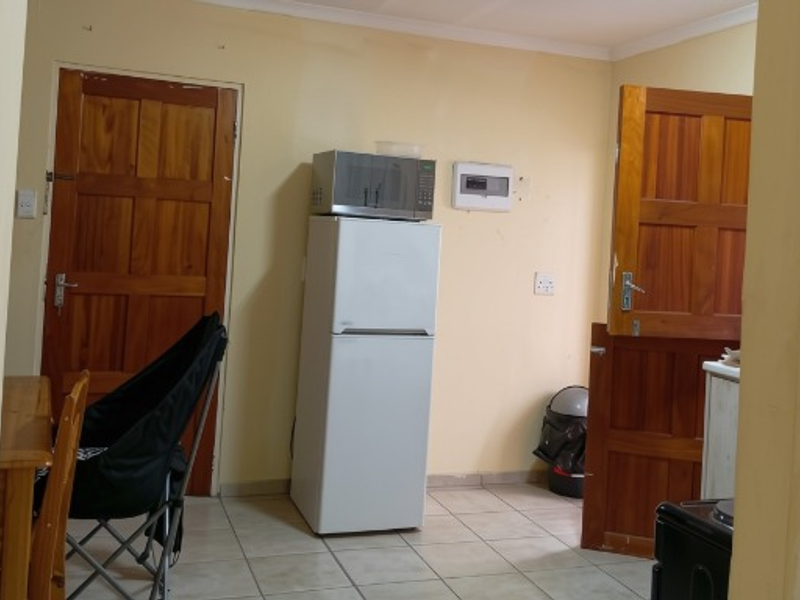 A functional kitchen area featuring tiled flooring and wooden doors, requiring cosmetic updates to improve the overall aesthetic and finish.
