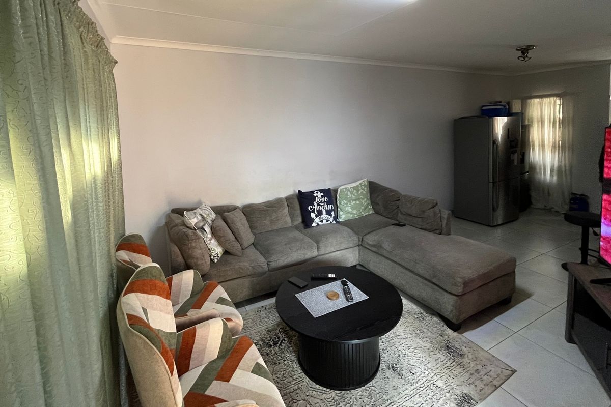 A functional living room area featuring tiled flooring and coved ceilings, providing a neutral base for potential interior updates.