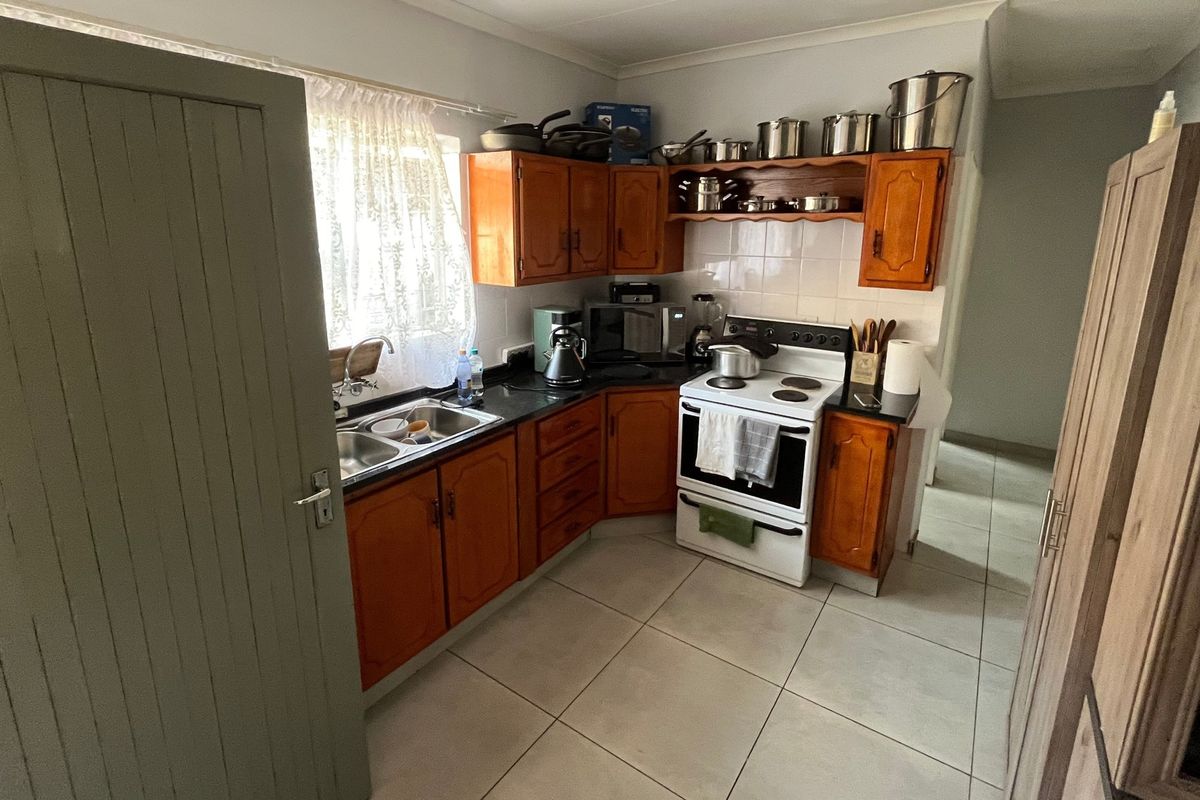 A functional kitchen featuring wooden cabinetry, laminate countertops, a double basin sink, and a freestanding stove with a tiled backsplash.
