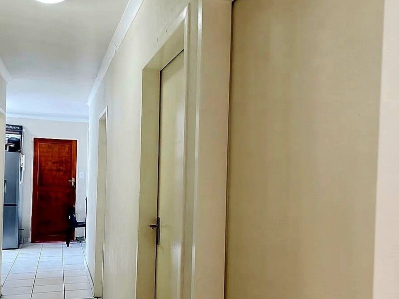 A functional hallway featuring tiled flooring, neutral walls, and built-in storage cupboards, providing access to various rooms within the home.