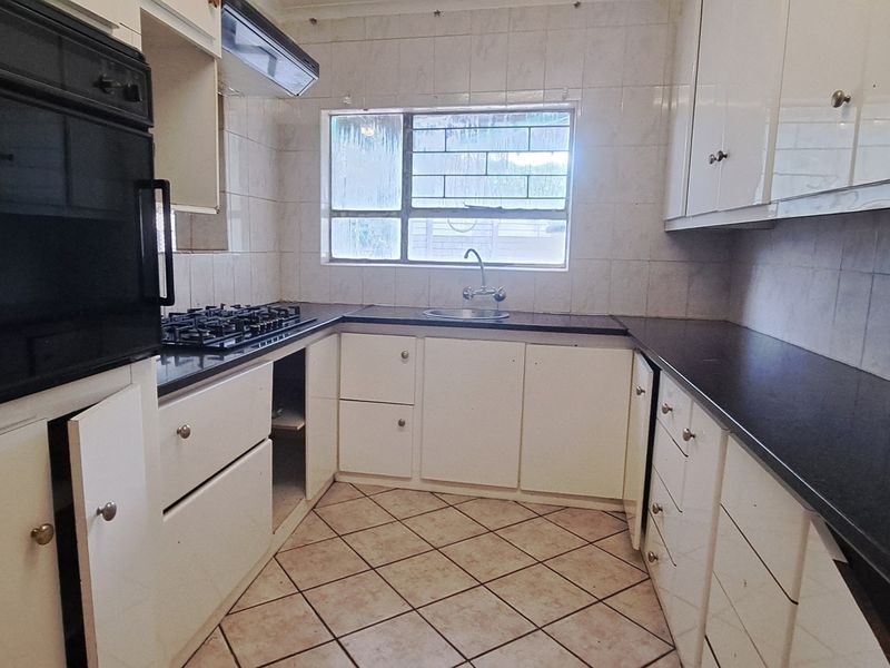 A functional kitchen featuring built-in cabinetry, a gas hob, an integrated oven, and tiled finishes, offering a blank canvas for modern renovation.