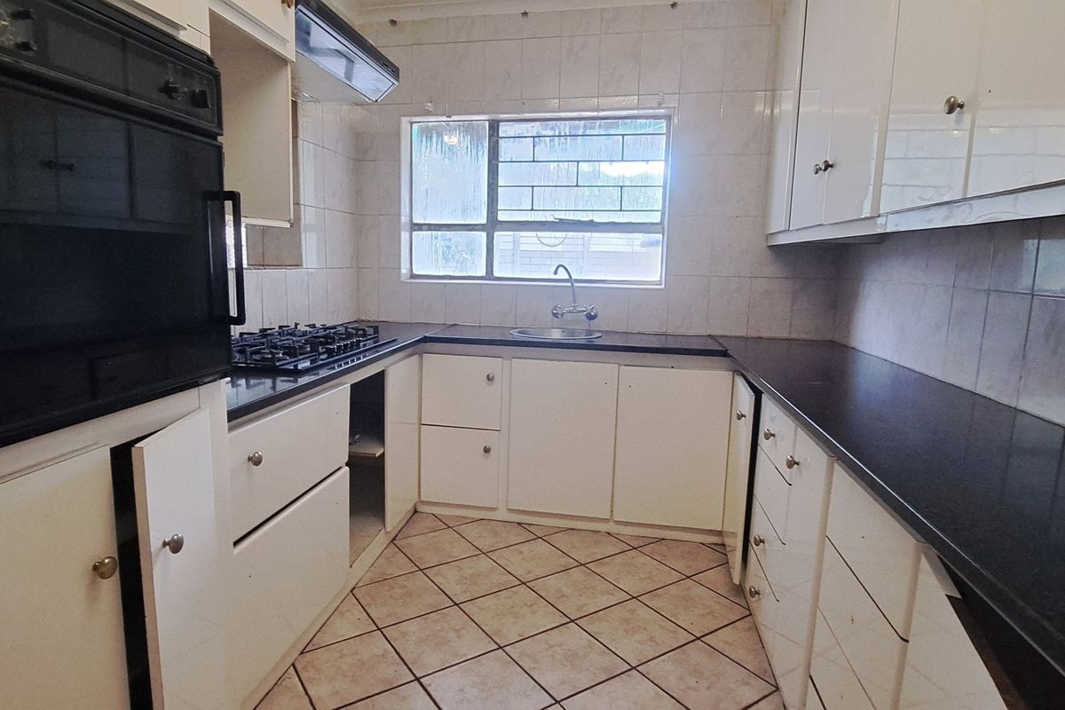A functional kitchen featuring built-in cabinetry, a gas hob, an integrated oven, and tiled finishes, offering a blank canvas for modern renovation.