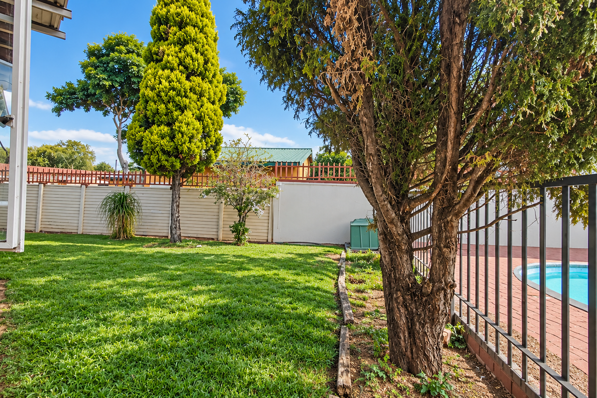 A rear garden area featuring a swimming pool with paved surround, enclosed by metal fencing and precast concrete boundary walls.
