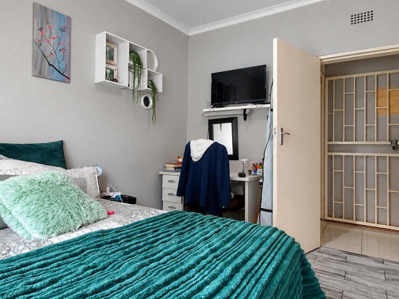 A well-maintained bedroom featuring tiled flooring and a secure entrance gate, providing a comfortable and functional living space.