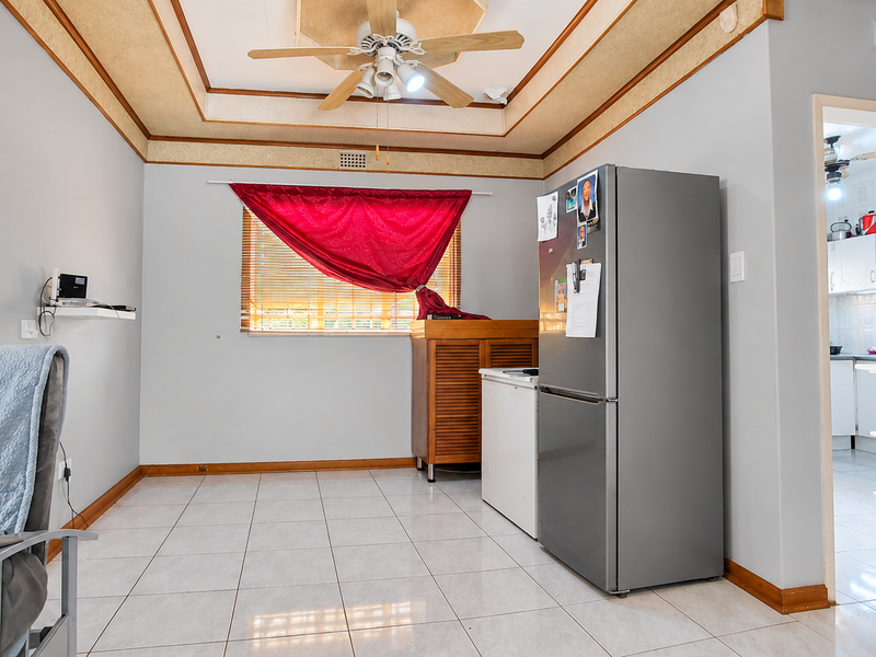 Open plan living area featuring tiled flooring, a tray ceiling with a central fan, and direct access to the adjacent kitchen space.