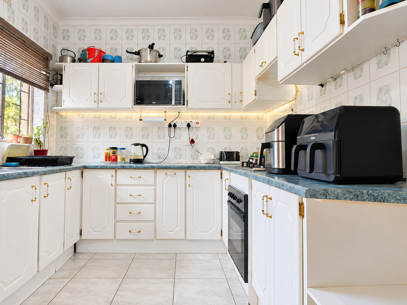 A functional kitchen featuring white cabinetry, laminate countertops, tiled walls, and built-in oven, offering a clean and practical workspace.