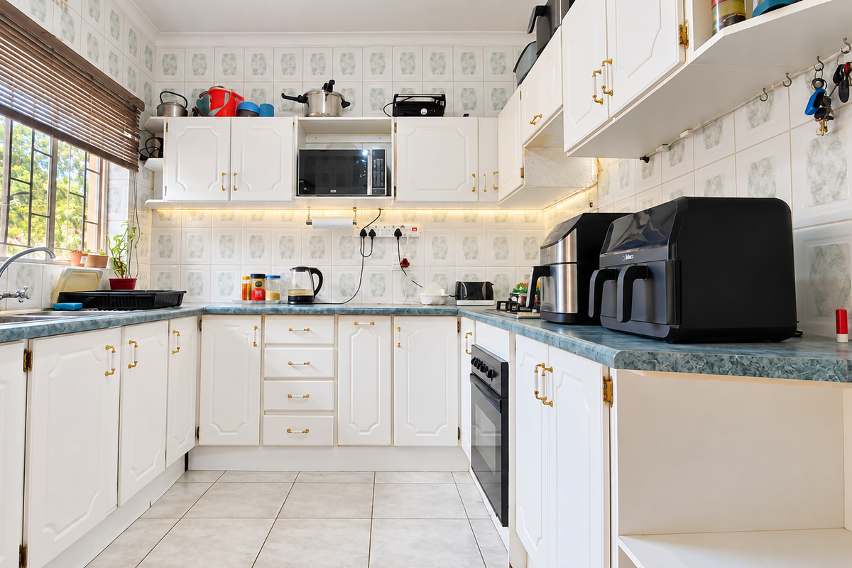 A functional kitchen featuring white cabinetry, laminate countertops, tiled walls, and built-in oven, offering a clean and practical workspace.