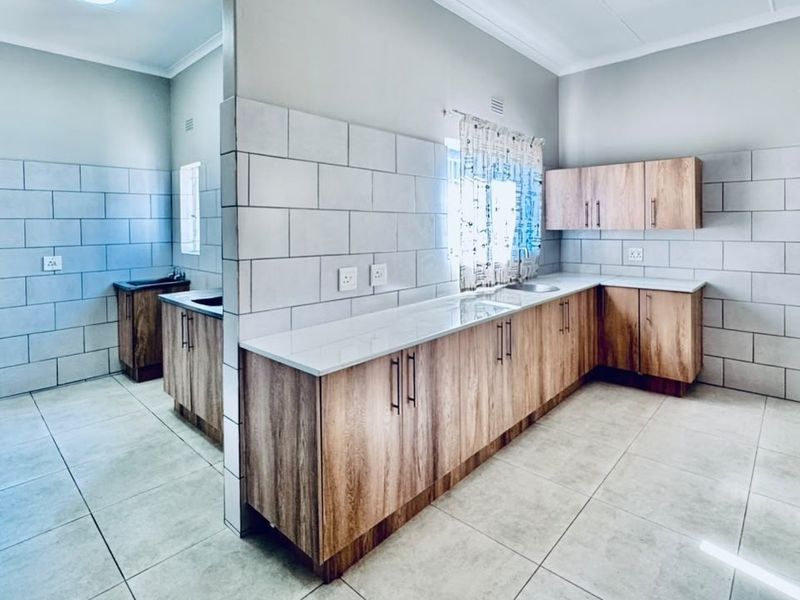 A modern, clean kitchen featuring wood-finish cabinetry, stone countertops, and a subway tile backsplash, offering a functional and bright workspace.