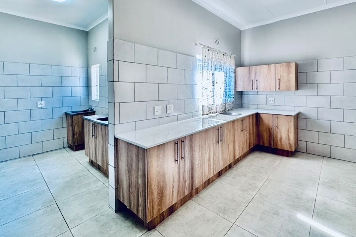 A modern, clean kitchen featuring wood-finish cabinetry, stone countertops, and a subway tile backsplash, offering a functional and bright workspace.