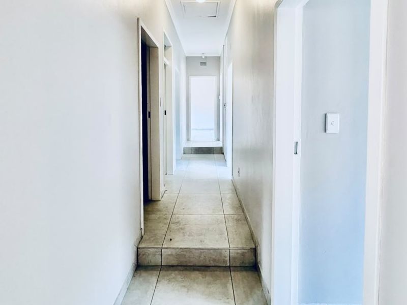 A functional hallway featuring tiled flooring and multiple access points to adjacent rooms, providing a clean and neutral transition space within the home.