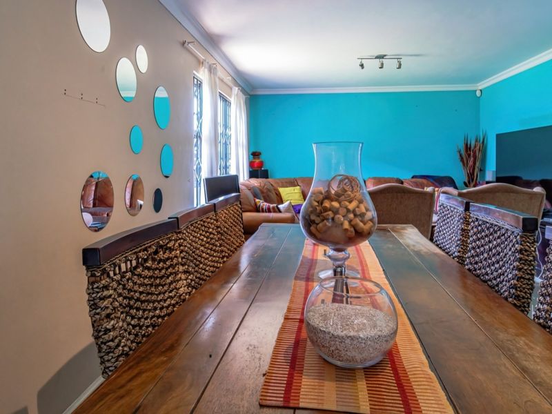 Open plan living and dining area featuring coved ceilings, track lighting, and security bars on windows.