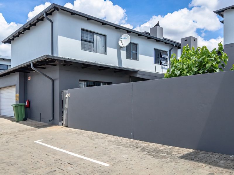 A modern double-story residential property featuring a paved driveway, secure boundary wall, and integrated garage access.
