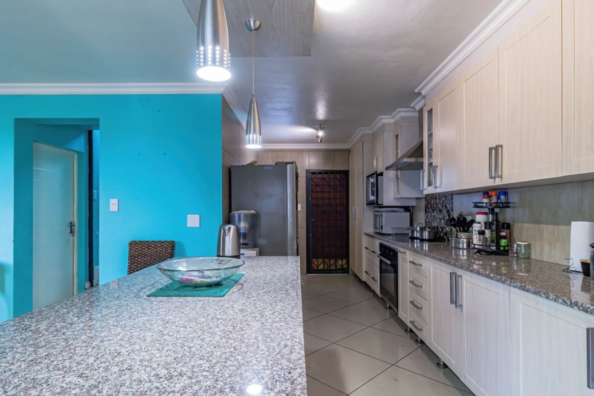 A functional kitchen featuring granite countertops, ample built-in cabinetry, a central island, and tiled flooring, providing a practical workspace for cooking and dining.