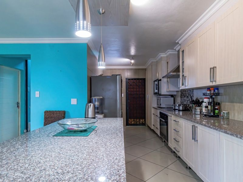 A functional kitchen featuring granite countertops, ample built-in cabinetry, a central island, and tiled flooring, providing a practical workspace for cooking and dining.