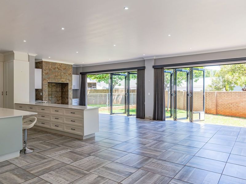 Spacious open-plan living area featuring a modern kitchen island, stone-clad fireplace, and large bi-fold doors opening to the rear garden.