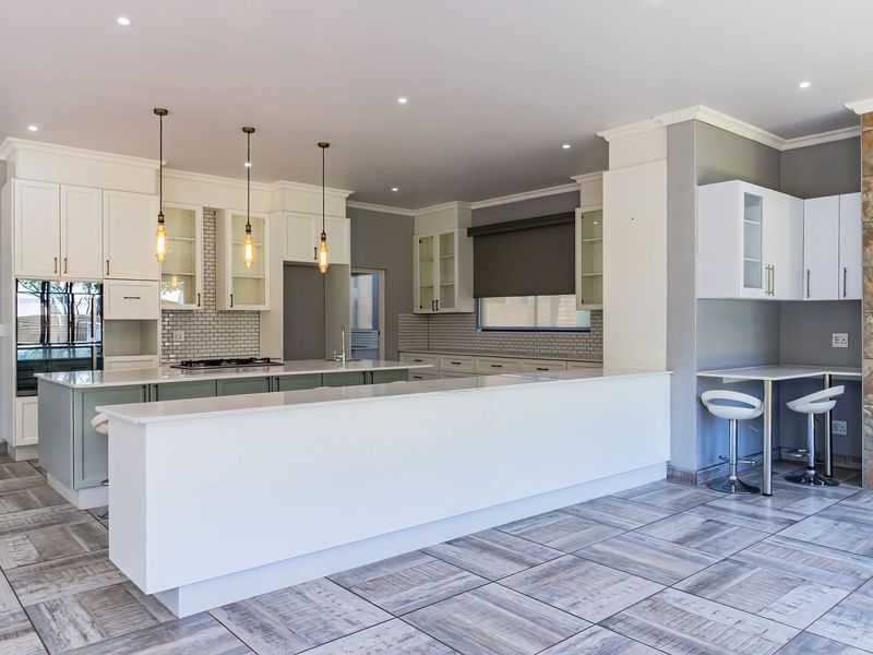 Modern kitchen featuring a large island with quartz countertops, subway tile backsplash, built-in appliances, and a striking stone feature wall.