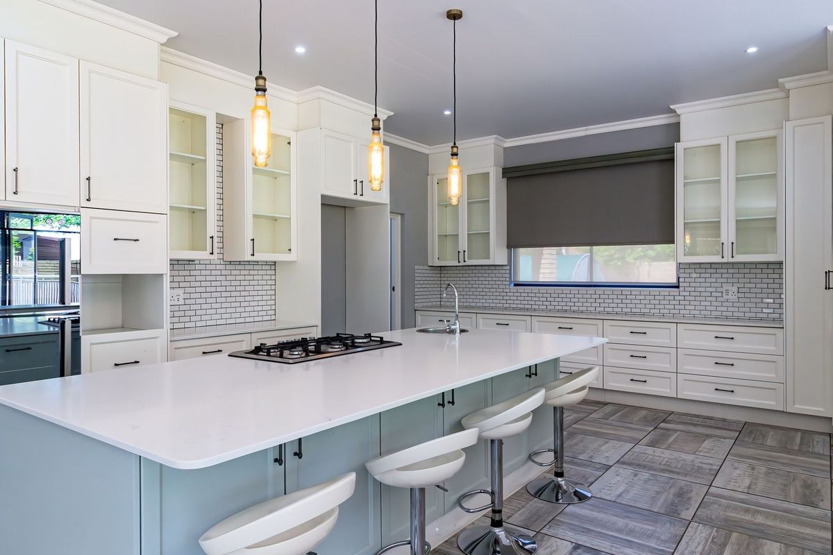 Modern kitchen featuring a large central island with quartz countertops, gas cooktop, shaker cabinetry, subway tile backsplash, and stylish pendant lighting.